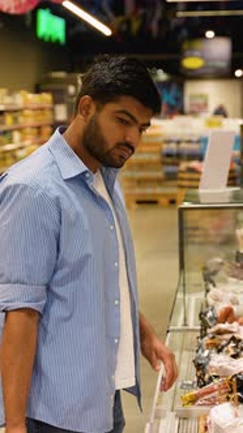 Pakistani Man Choosing Sliced Salami at Grocery Store