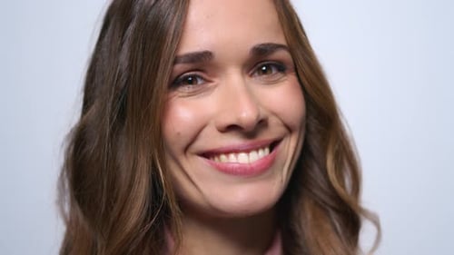 Une jeune femme joyeuse sourit et fait des grimaces en studio sur fond bleu