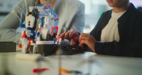 Close Up of Boy Studying Robotic Arm Model with Teacher in Primary School