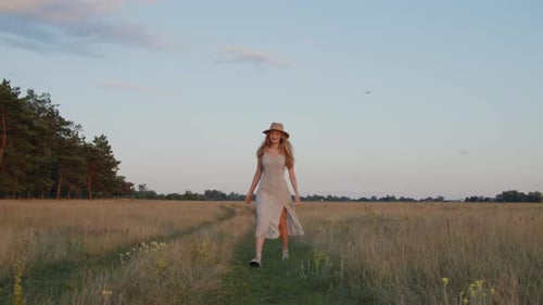 A Girl in a Hat Walks Across a Field