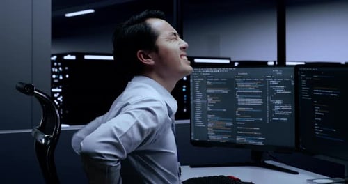Male Programmer Having A Backache While Writing Code By Desktops In The Server Room