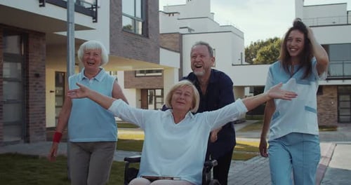 Joyful Senior Woman in Wheelchair Pushed by Friends