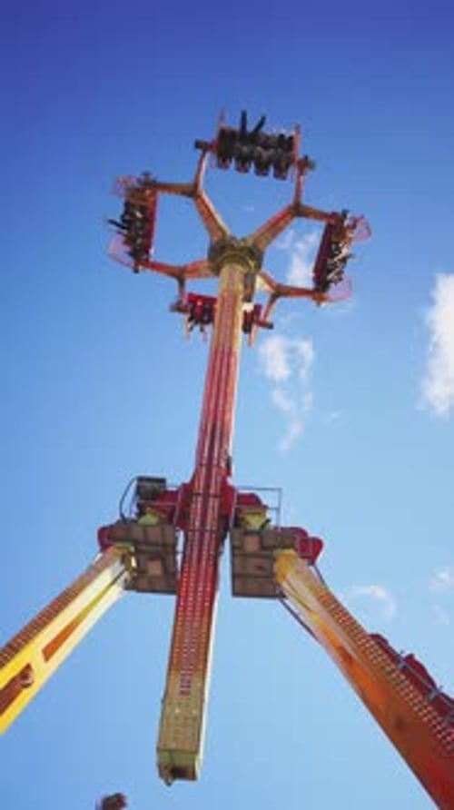 Lowangle View of a Thrilling Amusement Park Ride with Riders Upside Down Against a Clear Blue Sky