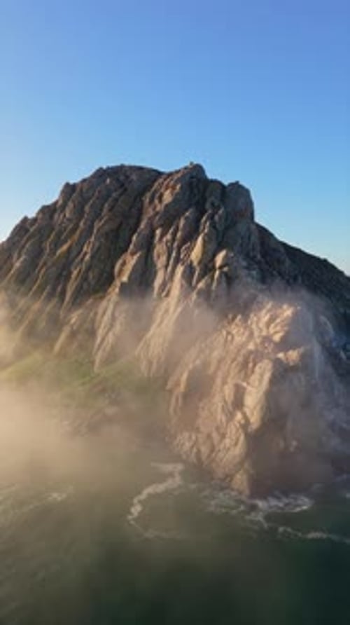 A Breathtakingly Stunning Rock Formation Surrounded By Enveloping Mist and Roaring Ocean Waves