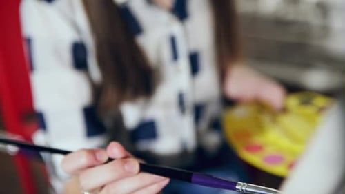 A Cute Toddler Girl Painting with Gouache Paints on the Easel Indoors