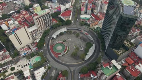 Drone flying in circles over roundabout in city of Mexico with cars and buildings
