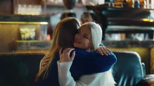Two Women on Sofa are Hugging and Supporting Each Other at the Cafe Slow Motion