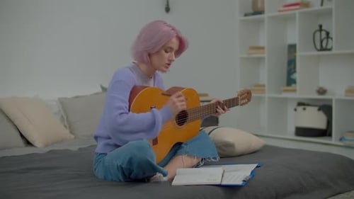 Thoughtful Charming Woman Songwriter with Guitar Writing Lyrics Into Notepad