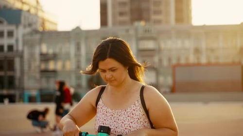 Das Mädchen, das einen sonnigen Tag genießt, fährt mit einem Elektroroller durch die Stadt
