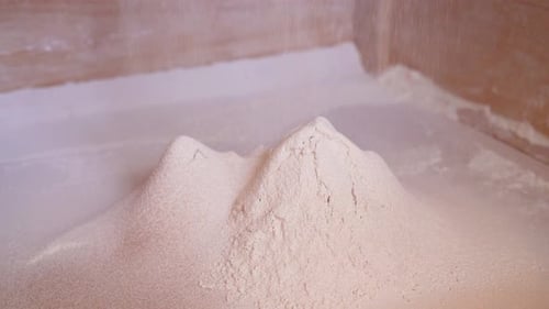 Slow Motion Close-Up of Flour Pile with Flour Being Poured Against Wooden Wall and Floor
