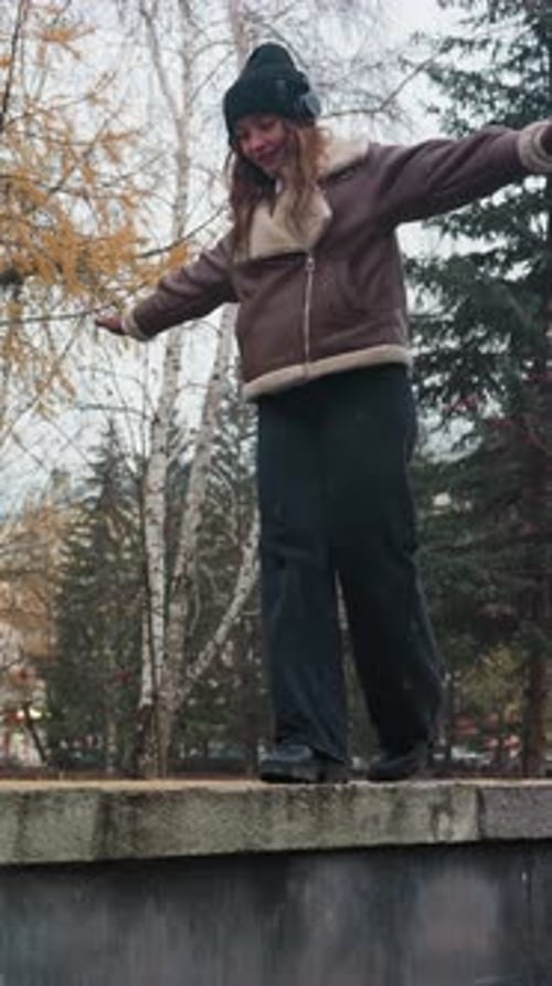 Dreamy Lady Balancing on Stone Wall in Autumn Park