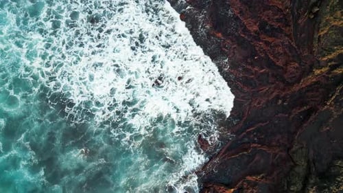 Dramatic Drone View of White Sea Foam Crashing on Rocks