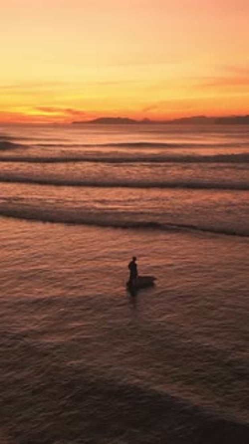 Männlicher Surfer an der Meeresküste zur Goldenen Stunde