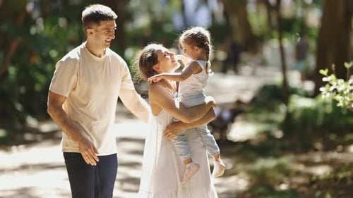 A Family Walks in the Park Mother Holding Her Daughter and Kissing Her in the Cheek