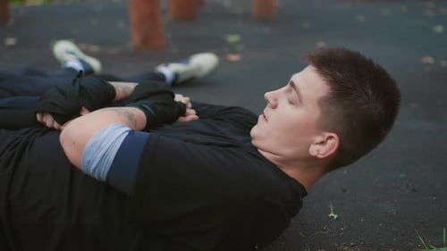 Man Recovering From Exercise in Urban Park Setting Close Up Athletic Male Lying on Ground During