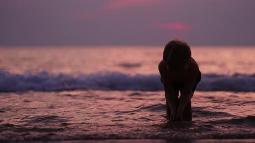 Boy Plays in Surf at Beach at Sunset
