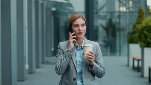 Businesswoman on the Phone Holding Coffee in an Urban Area
