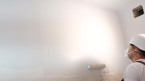 Man Painting Wall with Roller in Home