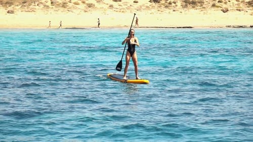 Woman paddling sup board in the sea super slow motion on sunny summer day