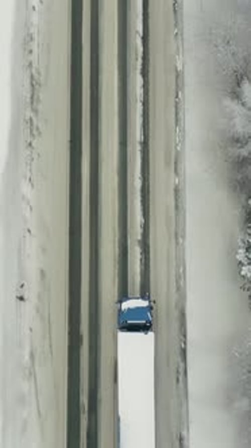 Vue aérienne de la circulation sur la route traversant la forêt hivernale en cas de mauvais temps