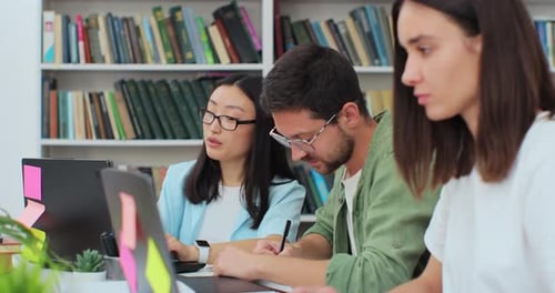 Friendly Students Sit at Desk in Library Writing Discuss Collaborative Project Preparing for High