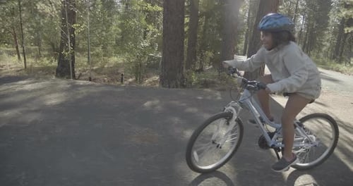 Biracial Girl Riding Bicycle in a Forest in Slow Motion