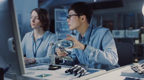Japanese Development Engineer in Blue Shirt is Soldering a Circuit Board in a High Tech Research La