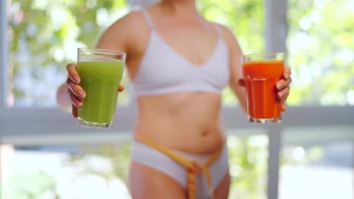 Woman Holding Healthy Green and Orange Vegetable Drinks