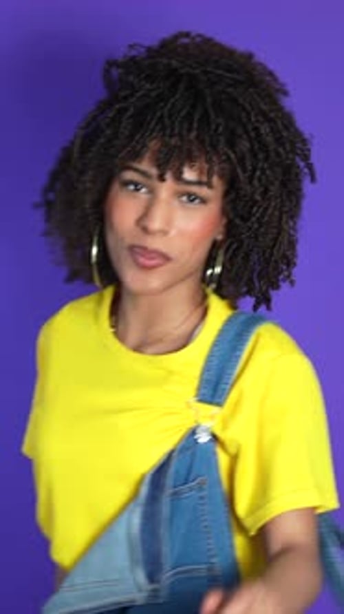 Young woman dancing and having fun on purple background