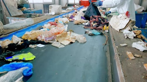 Workers in special wear sorting garbage on a conveyor belt at waste sorting plant