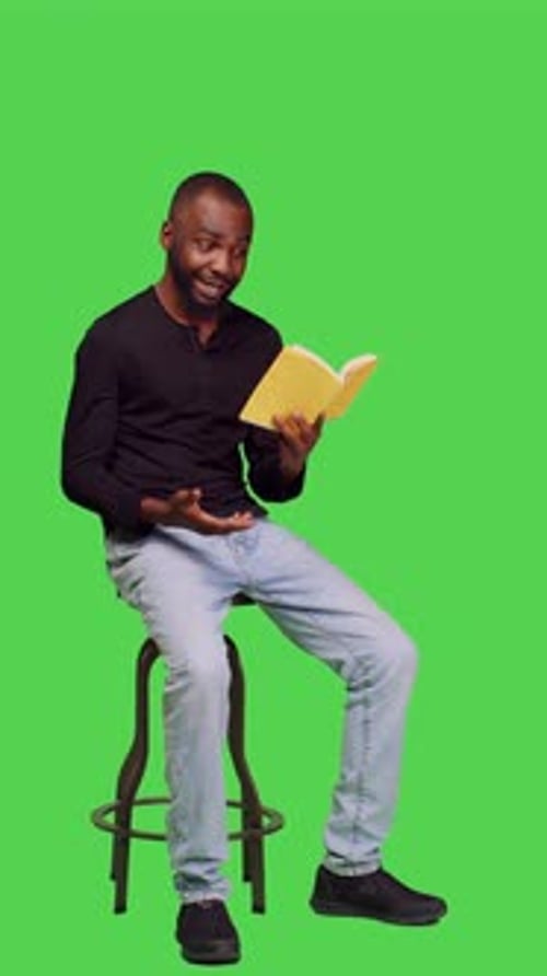 Vertical Video Side View of Male Model Reading Novel Story on Book in Studio
