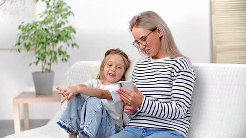 Woman and Child Looking at Phone on Couch