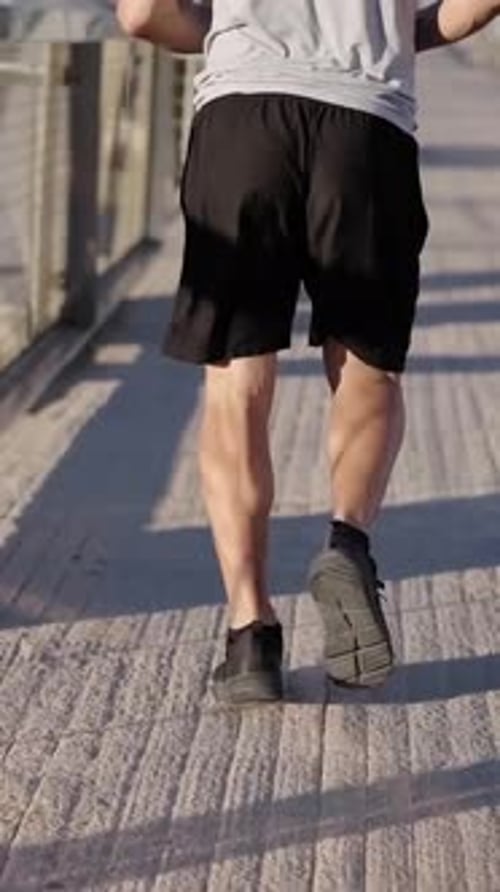 Unrecognizable Sport Mature Man Running Outdoors in the Morning Through a Bridge