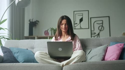 Young Woman Using Laptop on Couch at Home