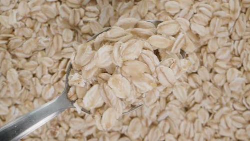 A spoon with oat flakes slowly rises upwards, with a background of rotating oats below.