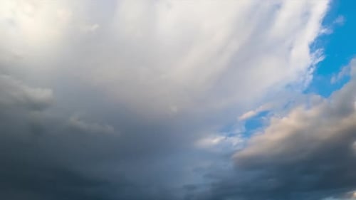 Big grey cloud in the blue summer sky. Rainy cloudscape accumulating in the atmosphere.