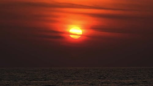 Dramatisch Sonnenaufgang mit orangefarbenem Himmel an einem bewölkten Tag am Meer.