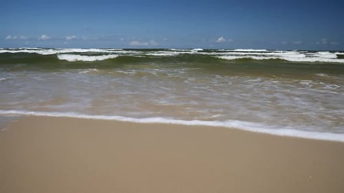 Wellen rollen am Sandstrand. Zeitlupe 60 bis 30 Bilder pro Sekunde.