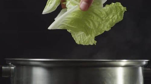 Hand Adding Green Cabbage to Steaming Pot