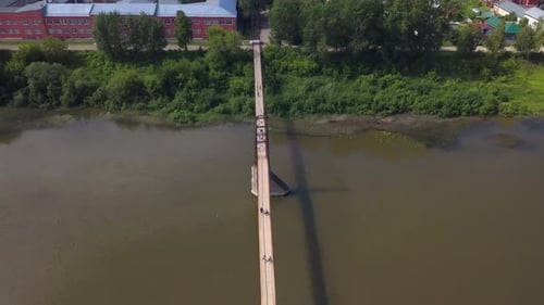 Old narrow bridge over a river. Clip. Drone flight over bridge above wide dirty river.