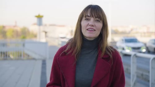 An Attractive Middleaged Caucasian Woman Talks to the Camera and Walks Alongside a Busy Road