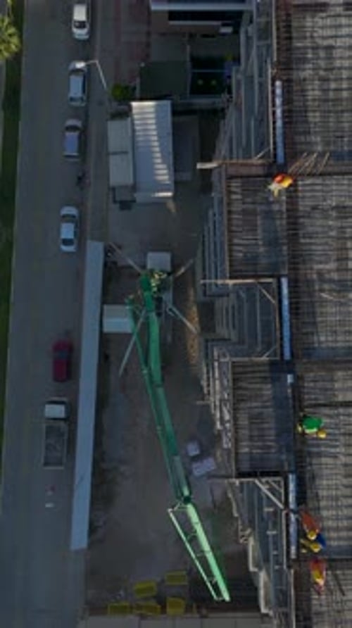 Vertical Video of Residential Construction With Workers Building Walls and a Crane Lifting Beams