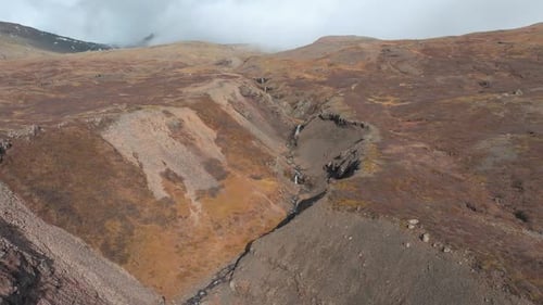 Stream cascading down a mountainside in Iceland in autumn - push in drone