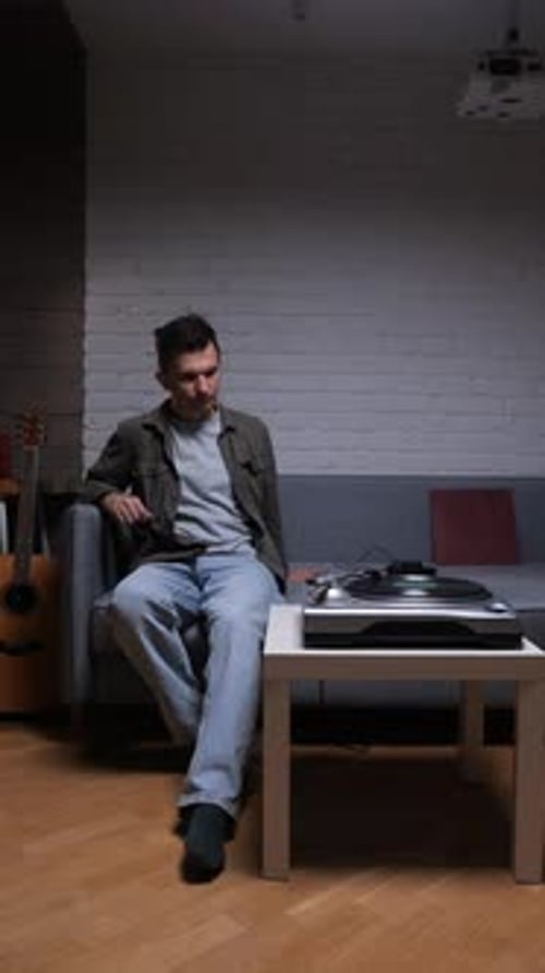 Vertical Video Young Man Sitting on a Sofa in a Modern Loft Apartment Enjoying His Free Time By