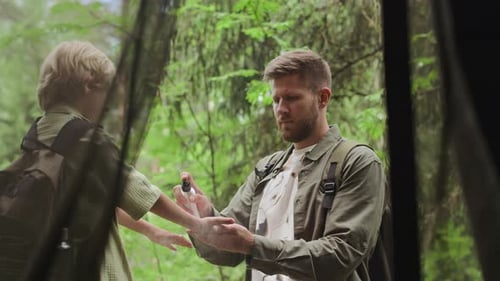 Father Applies Sunscreen to Child in Forest