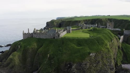 Aerial view passing through Scotland's Dunnottar Castle sitting above the ocean's cliffs.