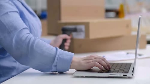 Close Up Laptop Checking Orders Scanning Barcode on Packages for Shipping Online Marketplace