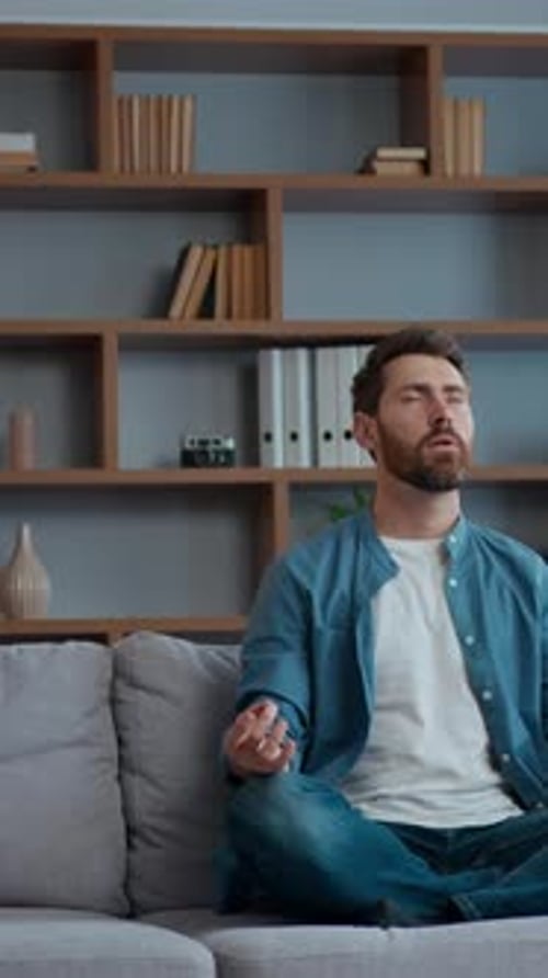 Father meditates while daughter jumps on couch