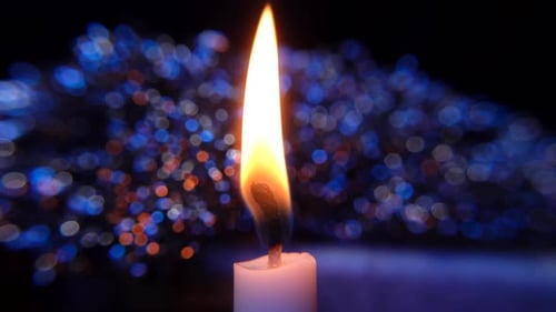 Close-up of a burning candle in a dark setting