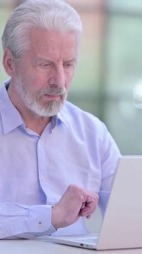 Senior Man Typing on Laptop in Modern Office